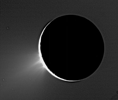 Enceladus mit seinen in Aktion befindlichen Eisvulkanen. Vermutlich ist dies Wasserdampf, der in der Kälte des Weltraums sofort kristallisiert. (Eine Aufnahme im Gegenlicht).